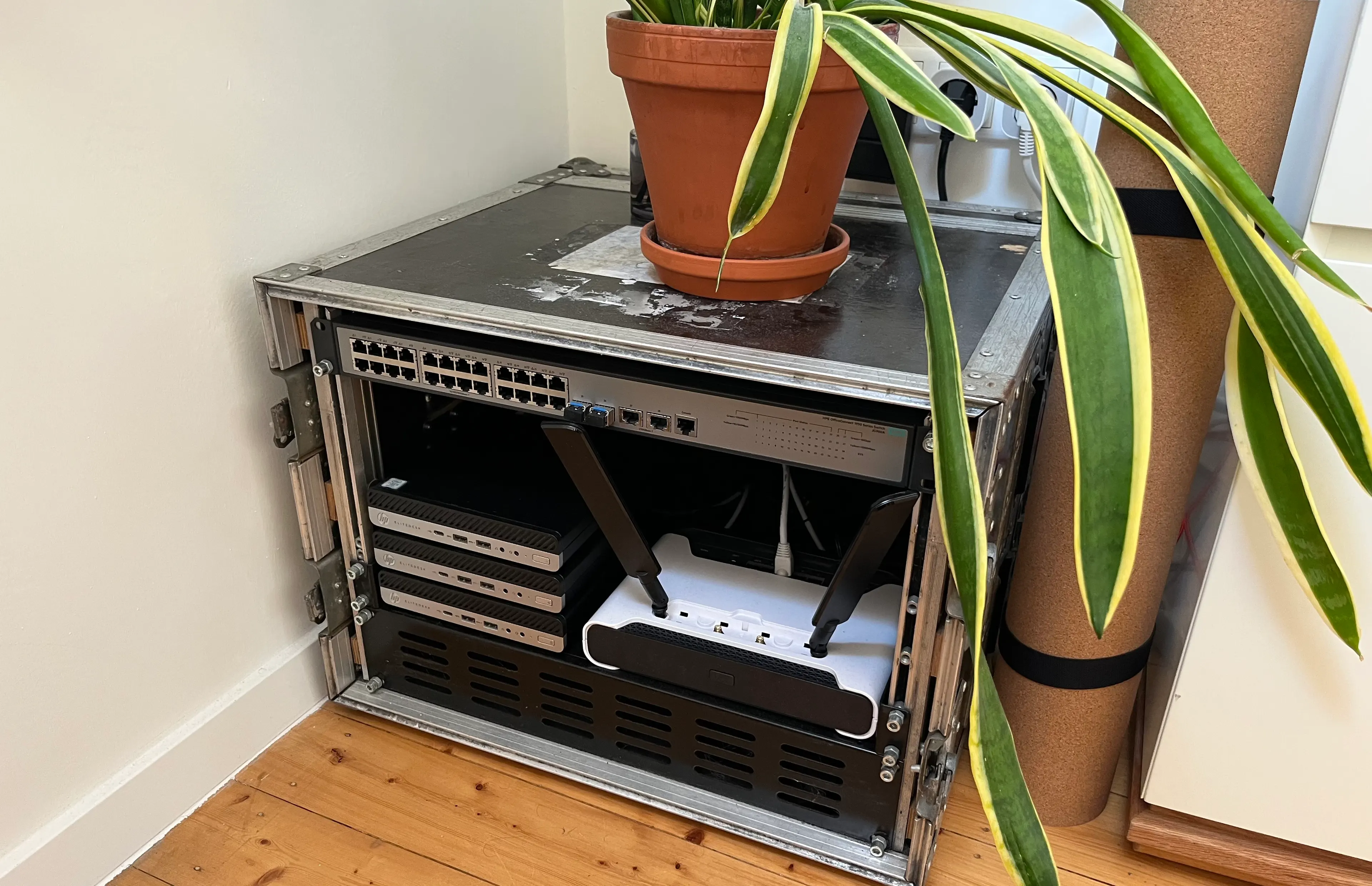 My homelab in a flightcase rack: three stacked HP EliteDesk minis and a Mikrotik Chateau 5G ax.